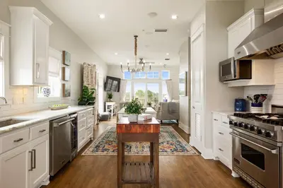 a kitchen with white cabinets and a wooden table at Paradise Found on 30A in Santa Rosa Beach