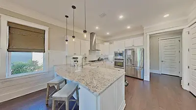 a kitchen with white cabinets and a island with bar stools at Prominence Southside - Blue Skies in Watersound Beach