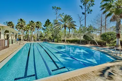 a swimming pool with blue water and palm trees at Pines and Palmettos in Santa Rosa Beach