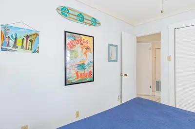 a bedroom with a bed and a poster on the wall at High Cotton Beach Cottage in Inlet Beach