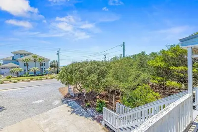 a house with a white fence next to a street at High Cotton Beach Cottage in Inlet Beach