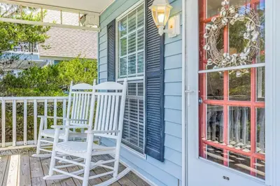 a porch with two chairs and a window at High Cotton Beach Cottage in Inlet Beach