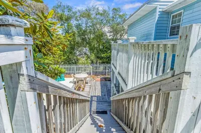 a wooden fence next to a blue house at High Cotton Beach Cottage in Inlet Beach