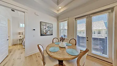 a dining room with a table and chairs and windows at Settle By The Sea in Inlet Beach