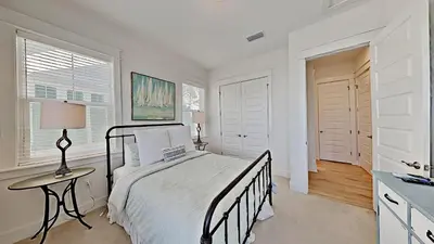 a bedroom with a bed and a table and two windows at Settle By The Sea in Inlet Beach