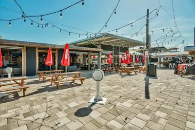 a patio with wooden benches and red umbrellas at Prominence on 30A - Mint to Relax in Inlet Beach