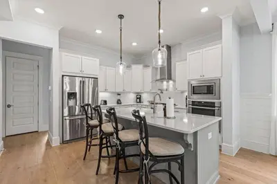 a kitchen with white cabinets and a island with bar stools at Crabbing Hole Lane in Rosemary Beach