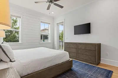 a bedroom with a bed and a flat screen tv at Crabbing Hole Lane in Rosemary Beach