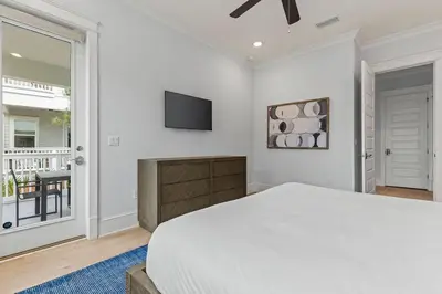 a white bedroom with a bed and a tv at Crabbing Hole Lane in Rosemary Beach