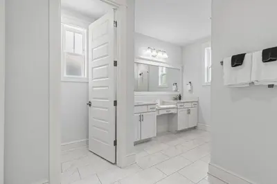 a white bathroom with a sink and a mirror at Crabbing Hole Lane in Rosemary Beach