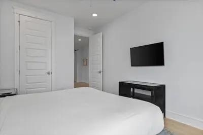a white bedroom with a bed and a television at Crabbing Hole Lane in Rosemary Beach