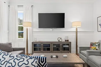 a living room with a flat screen tv on a wall at Crabbing Hole Lane in Rosemary Beach