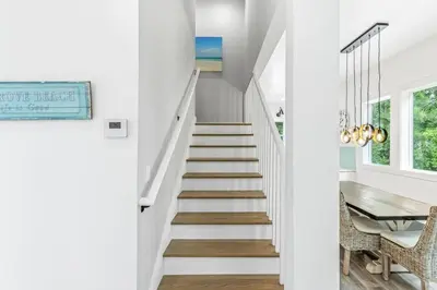 a staircase in a home with white walls and a table at Shore To Please in Santa Rosa Beach