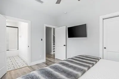 a white bedroom with a bed and a flat screen tv at Shore To Please in Santa Rosa Beach