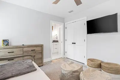 a white living room with a tv on a wall at Shore To Please in Santa Rosa Beach