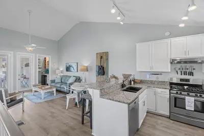 a kitchen with white cabinets and a living room at Time To Coast in Santa Rosa Beach