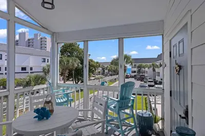 a balcony with chairs and a table and a view of a street at Time To Coast in Santa Rosa Beach