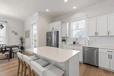 a kitchen with white cabinets and a kitchen island with chairs at Casa Del Sol - Inlet Beach in Inlet Beach