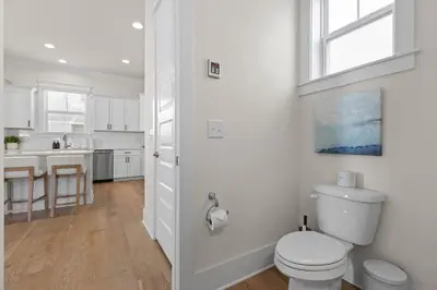 a white bathroom with a toilet and a kitchen at Casa Del Sol - Inlet Beach in Inlet Beach