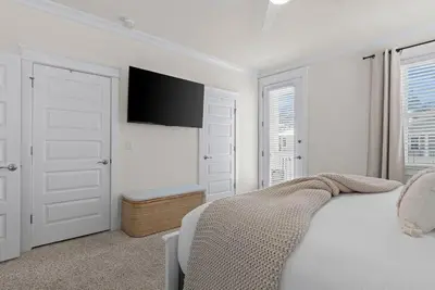a white bedroom with a bed and a flat screen tv at Casa Del Sol - Inlet Beach in Inlet Beach