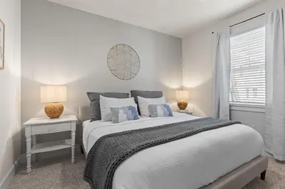 a white bedroom with a large bed with blue pillows at Casa Del Sol - Inlet Beach in Inlet Beach
