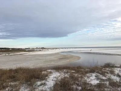 a beach with people walking on the sand and water at The Little Pearl on 30A's Eastern Lake in Santa Rosa Beach