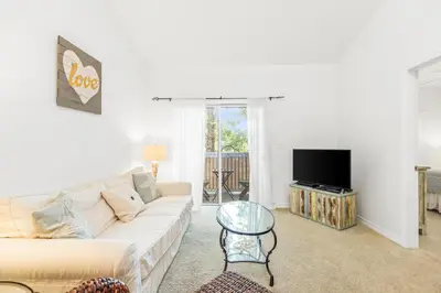 a living room with a white couch and a tv at The Little Pearl on 30A's Eastern Lake in Santa Rosa Beach