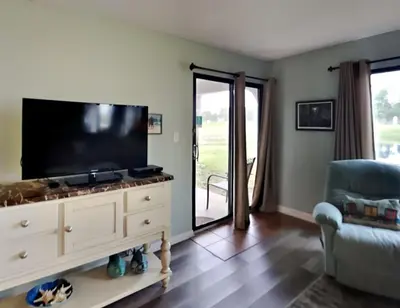 a living room with a flat screen tv on a dresser at Edgewater Villa 1908 in Panama City Beach