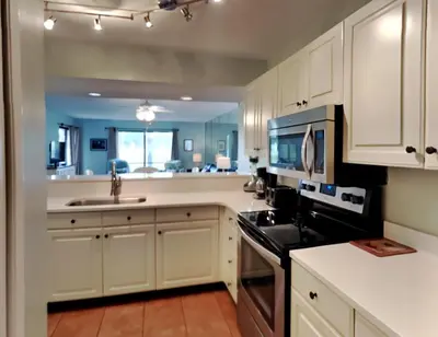 a kitchen with white cabinets and a sink and a microwave at Edgewater Villa 1908 in Panama City Beach
