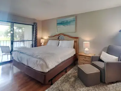 a bedroom with a large bed and a chair at Edgewater Villa 1913 in Panama City Beach