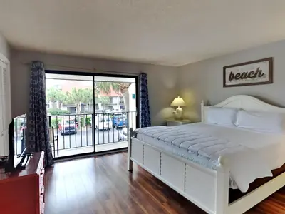a bedroom with a white bed and a balcony at Edgewater Villa 1913 in Panama City Beach