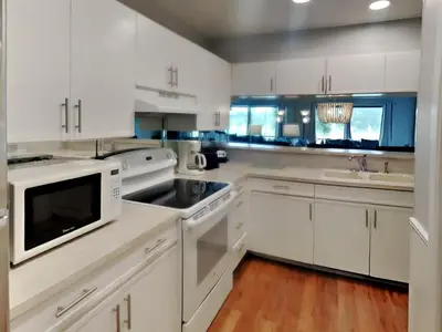 a white kitchen with white cabinets and a sink at Edgewater Villa 1913 in Panama City Beach