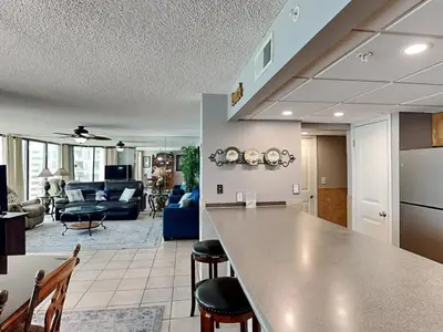 a kitchen and living room with a counter and chairs at Edgewater Tower III 513 in Panama City Beach