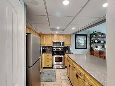 a kitchen with wooden cabinets and stainless steel appliances at Edgewater Tower III 513 in Panama City Beach