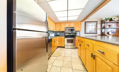 a kitchen with wooden cabinets and a stainless steel refrigerator at Edgewater Tower III 513 in Panama City Beach