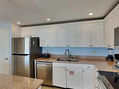 a kitchen with white cabinets and a stainless steel refrigerator at Edgewater Tower III #713 in Panama City Beach