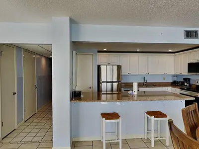 a kitchen with white cabinets and a counter with stools at Edgewater Tower III #713 in Panama City Beach