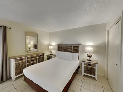 a bedroom with a white bed and two nightstands and a mirror at Edgewater Tower III #713 in Panama City Beach