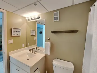 a bathroom with a sink and a toilet and a mirror at Edgewater Tower III 911 in Panama City Beach