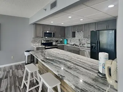 a kitchen with a large counter with two stools at Edgewater Tower III #1002 in Panama City Beach