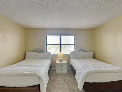 two beds in a room with a window at Edgewater Villa 117 in Panama City Beach