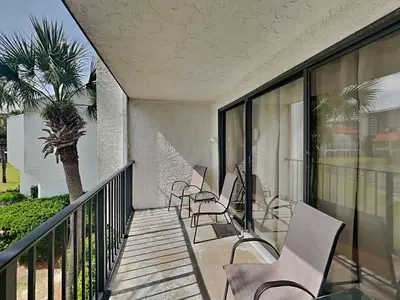 a balcony with chairs and a palm tree at Edgewater Villa 124 in Panama City Beach