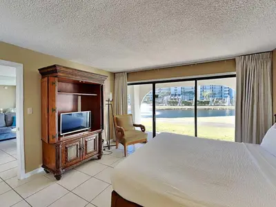 a bedroom with a bed and a tv and a chair at Edgewater Villa #502 in Panama City Beach