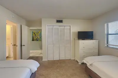 a bedroom with two beds and a dresser and a television at Edgewater Villa #506 in Panama City Beach