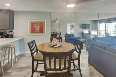 a dining room and living room with a table and chairs at Edgewater Villa #512 in Panama City Beach