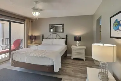 a bedroom with a bed and two tables and a mirror at Edgewater Villa #512 in Panama City Beach
