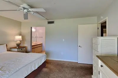 a bedroom with a white bed and a bathroom at Edgewater Villa #602 in Panama City Beach