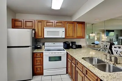 a kitchen with a white refrigerator and a sink at Edgewater Villa #604 in Panama City Beach