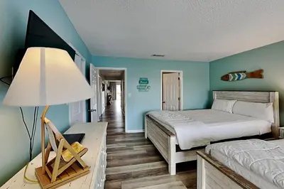 a bedroom with two beds and a table with a lamp at Edgewater Villa #712 in Panama City Beach