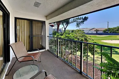 a balcony with a chair and a view of a golf course at Edgewater Villa #2011 in Panama City Beach
